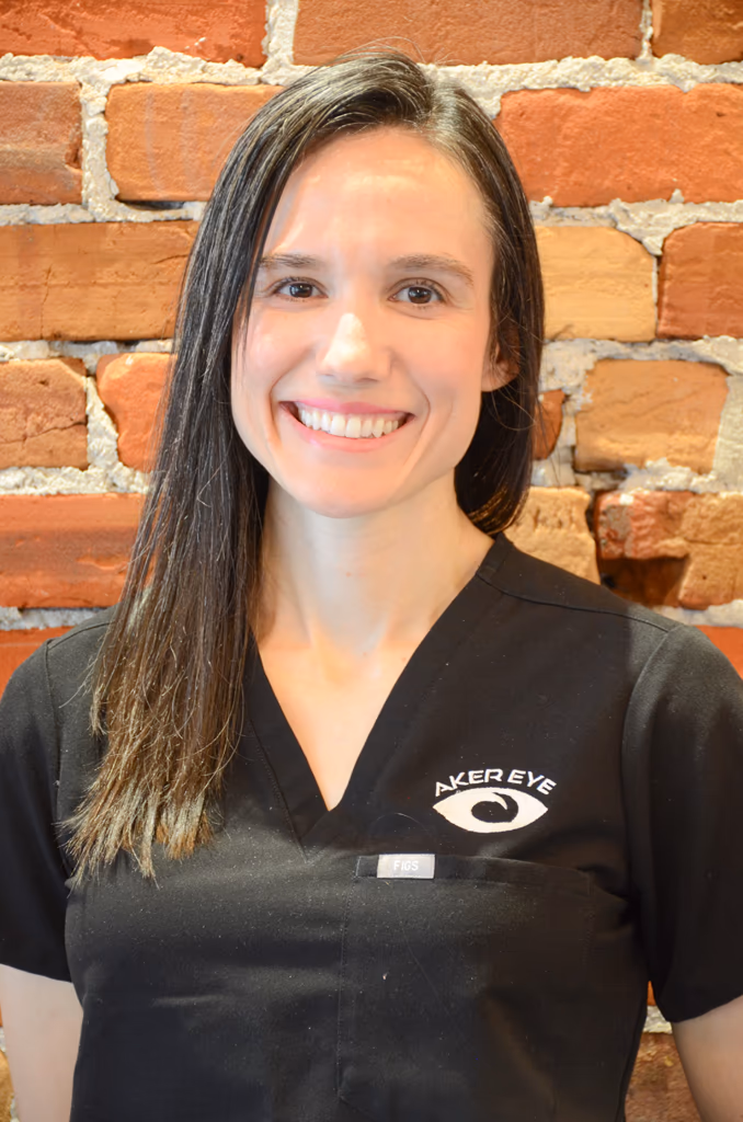 Dr. Amanda Aker, optometrist at Aker Eye in Titusville, smiling in black scrubs in front of a brick wall