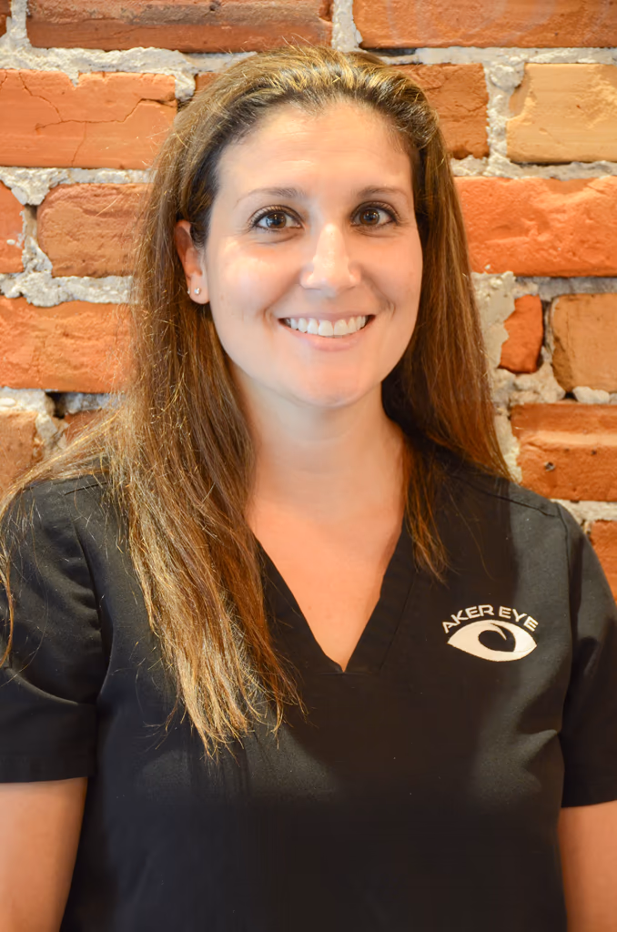 Dr. Jennifer Bradley, optometrist at Aker Eye in Titusville, in black scrubs in front of a brick wall