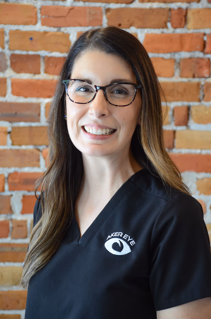 Dr. Sarah Koehnemann, optometrist at Aker Eye in Titusville, in black scrubs in front of a brick wall